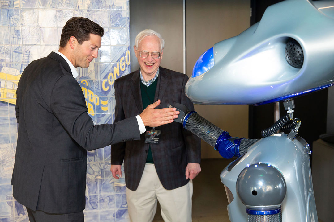 A guest gives a high-five to a life-size robot interacting with event guests.